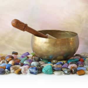 tibetan singing bowl with mallet against a smoky effect background sitting on a selection of …